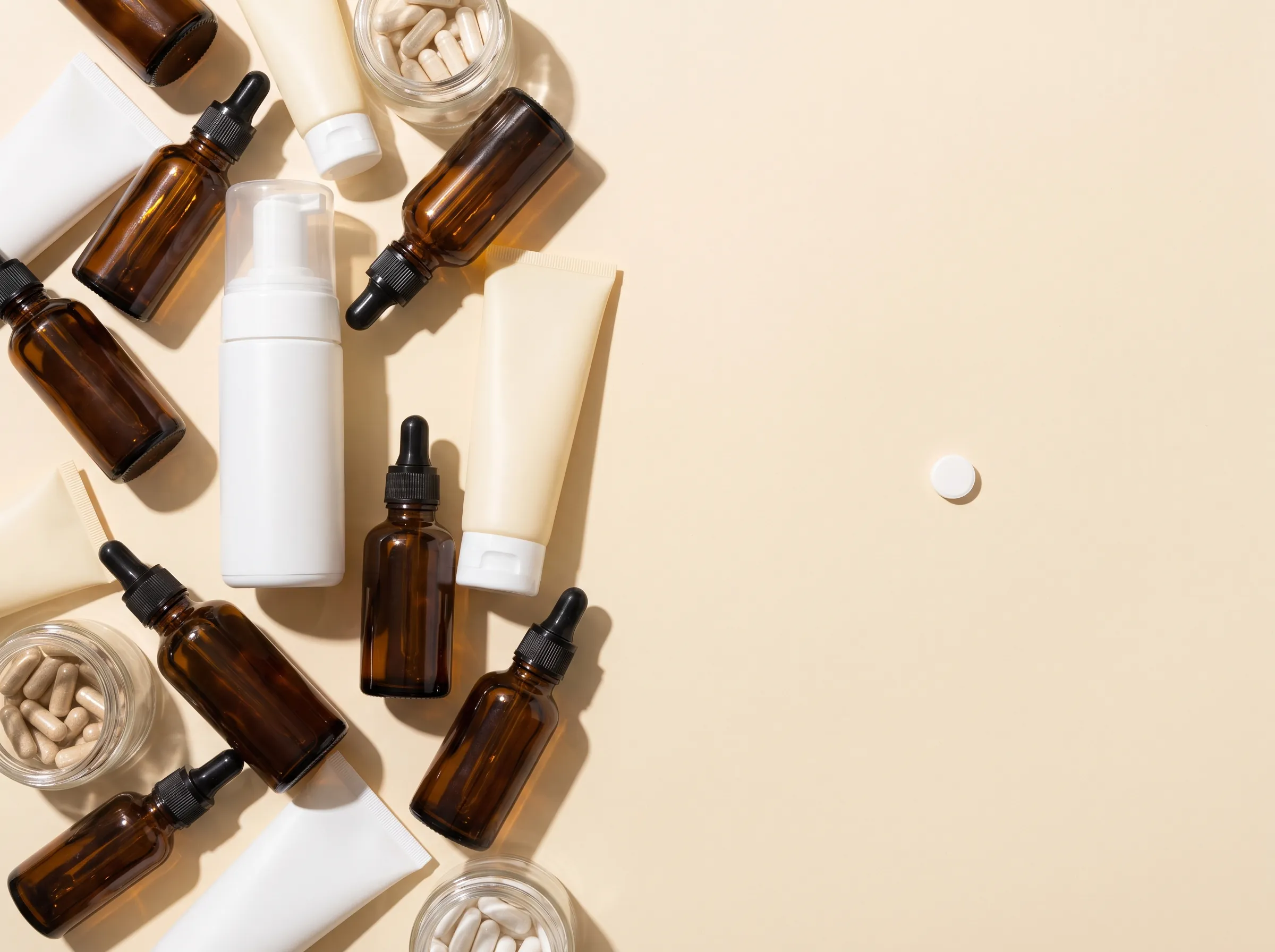 A cluttered pile of unlabeled hair products beside a single tablet on a clean surface