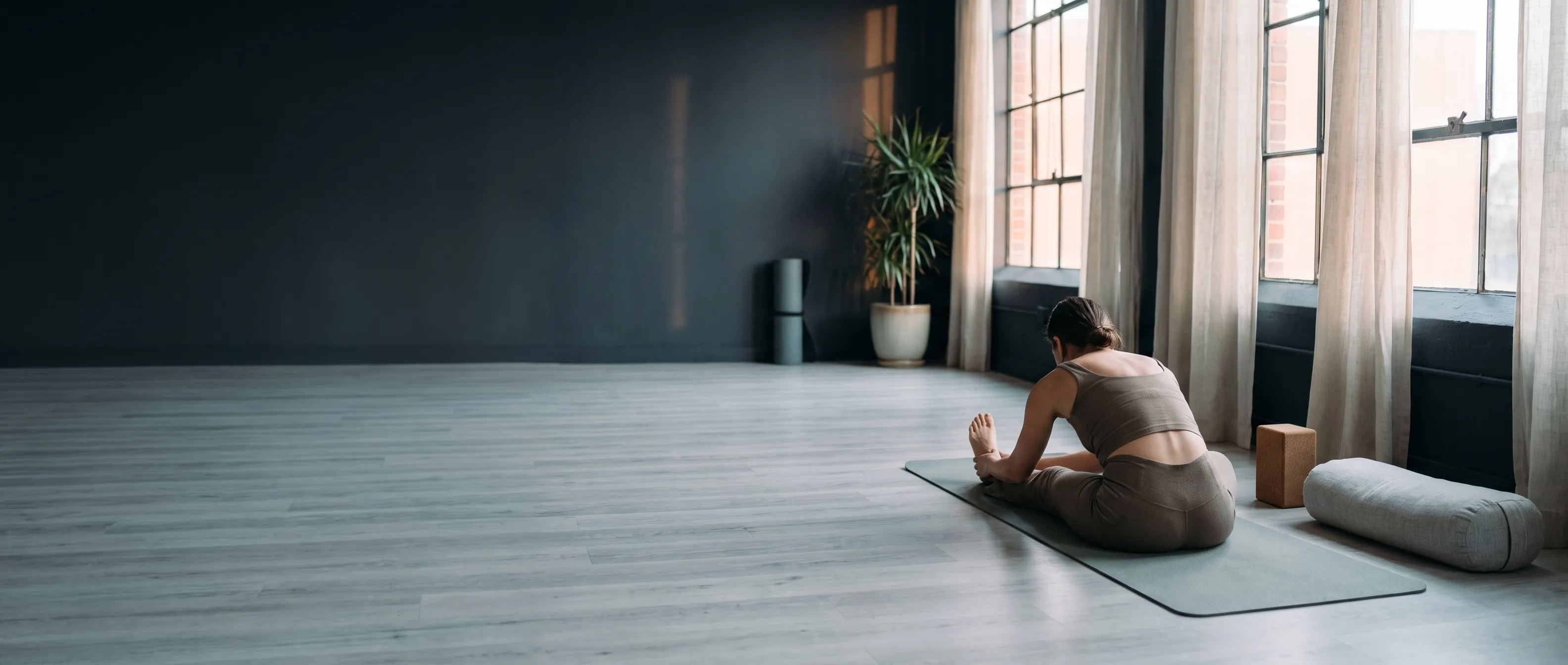 A woman in a deep hamstring stretch on a yoga mat in a serene studio
